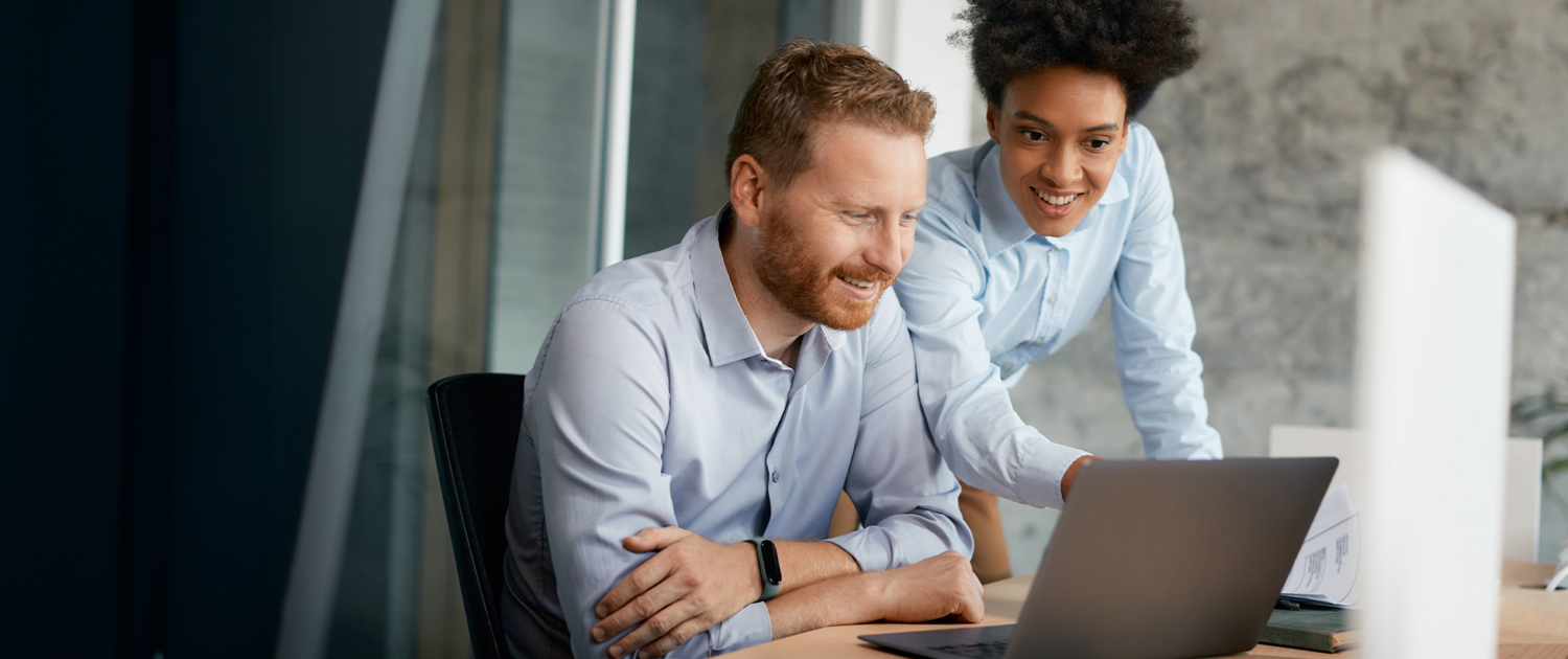 Two business colleagues cooperate while using laptop and work in office