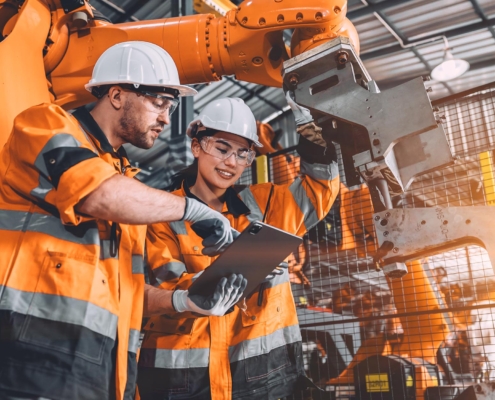 Two workers in manufacturing facility looking at tablet