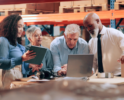 workers in warehouse looking at laptop