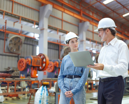 Two workers at manufacturing facility looking at laptop