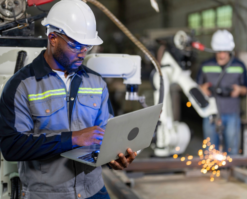 African mechanical engineer working for maintenance or repairing robotic welding machine in factory
