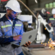 African mechanical engineer working for maintenance or repairing robotic welding machine in factory